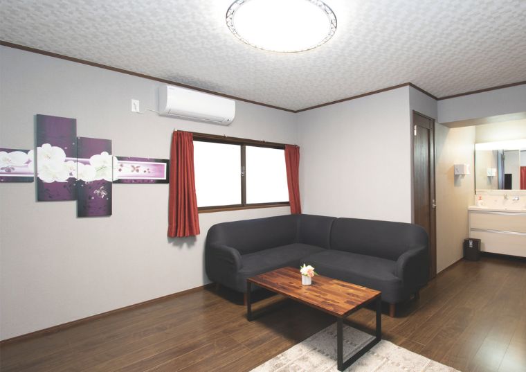 春日部市にある家族葬のアート春日部で提供する控室の黒ソファと木製テーブルが置かれた落ち着いた控室