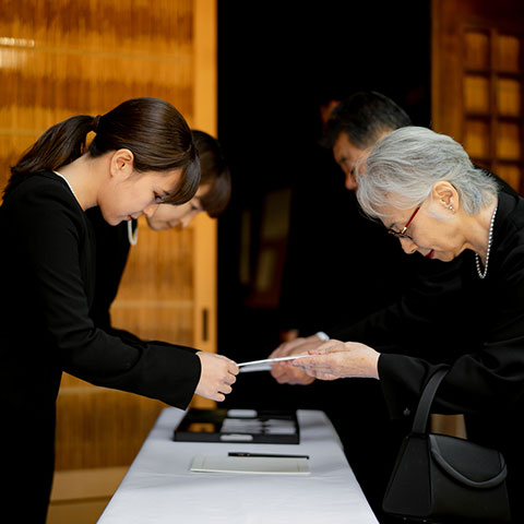 受付で参列者が香典を渡す場面