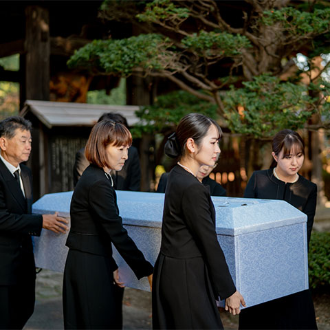 白い棺を搬送する出棺場面