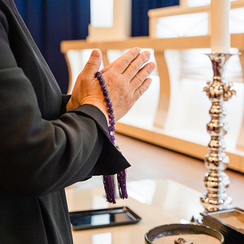 式場で合掌する遺族の手元と数珠