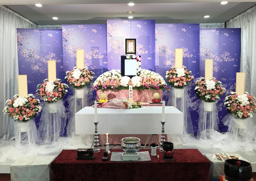 桜柄の紫背景とピンク白の生花祭壇の葬儀会場